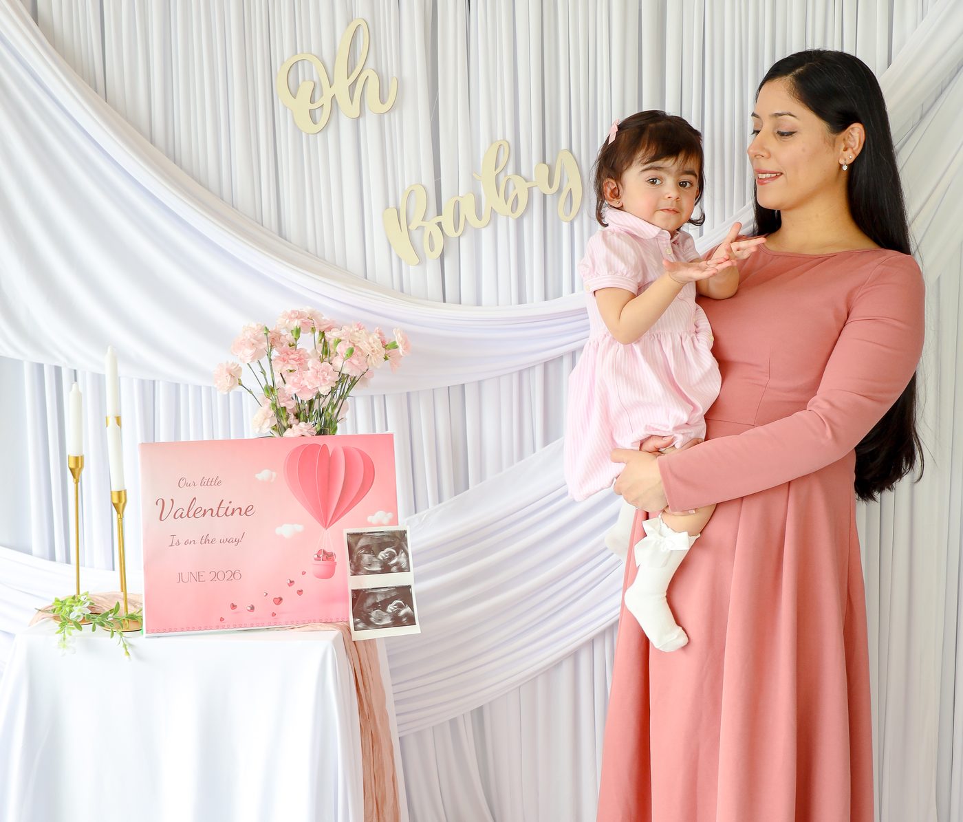 Mother holding her daughter in front of white drapes
