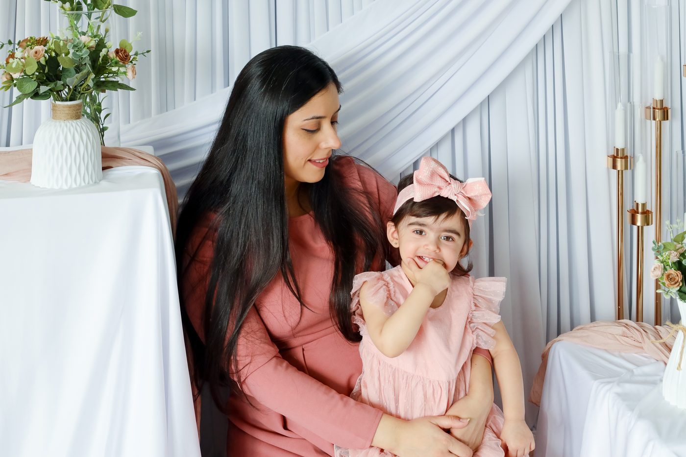 Mother and daughter seated together in soft pink