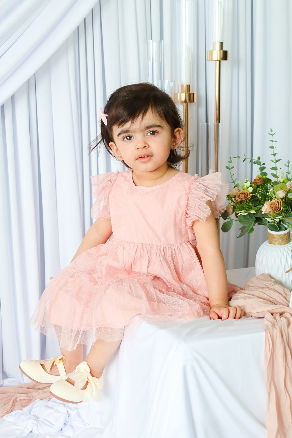 Little girl in a pink tulle dress seated on a table